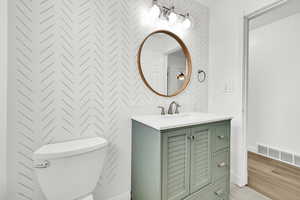 Bathroom with hardwood / wood-style flooring, vanity, and toilet