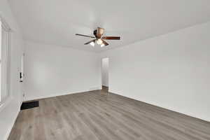 Empty room with ceiling fan and light hardwood / wood-style floors