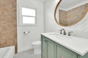 Full bathroom with vanity, tile patterned floors, toilet, and shower / bath combination