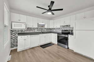 Kitchen with sink, light wood-type flooring, white appliances, decorative backsplash, and white cabinets