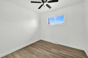 Empty room with ceiling fan and wood-type flooring