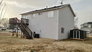 Back of house with a lawn, a deck, and central air condition unit