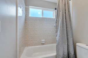 Bathroom with shower / bath combination with curtain and toilet