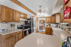 Kitchen featuring sink, an inviting chandelier, vaulted ceiling with beams, stainless steel appliances, and tasteful backsplash