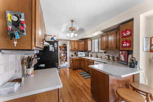 Kitchen with sink, a kitchen bar, decorative backsplash, kitchen peninsula, and light wood-type flooring