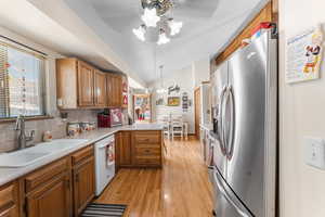 Kitchen with stainless steel refrigerator with ice dispenser, sink, dishwasher, kitchen peninsula, and pendant lighting