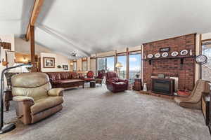 Carpeted living room featuring lofted ceiling with beams and a brick fireplace