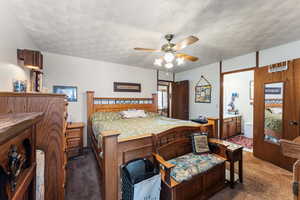 Carpeted bedroom featuring ceiling fan, connected bathroom, and a textured ceiling