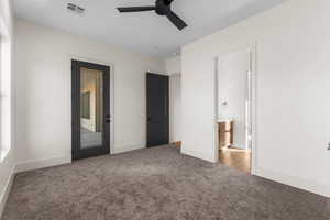 Unfurnished bedroom featuring ceiling fan, ensuite bathroom, and carpet floors