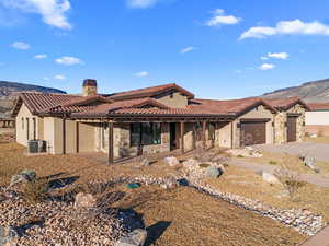 View of front facade with cooling unit, a garage, and a mountain view