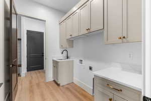 Laundry room featuring sink, washer hookup, cabinets, hookup for an electric dryer, and light hardwood / wood-style floors