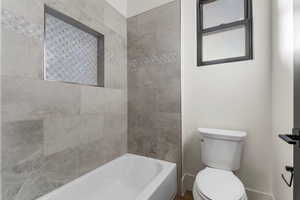 Bathroom with tiled shower / bath and toilet