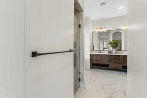 Bathroom featuring a shower with door and vanity