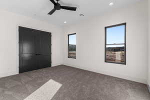 Unfurnished bedroom with ceiling fan, a closet, multiple windows, and carpet flooring