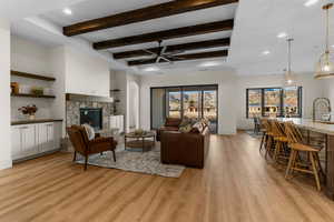 Living room featuring light hardwood / wood-style floors, ceiling fan, a textured ceiling, a fireplace, and sink