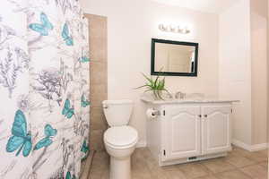 Bathroom with vanity, a shower with shower curtain, tile patterned floors, and toilet