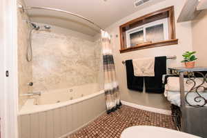 Bathroom featuring shower / jetted tub combo and toilet