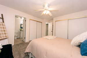 Bedroom featuring light carpet, ceiling fan, multiple closets, and bathroom