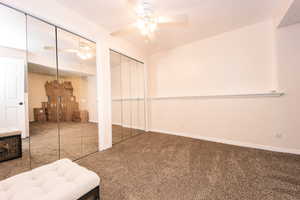 Basement bedroom with ceiling fan, mirrored closet,  and carpet floors