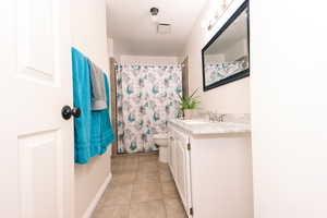 Bathroom with vanity, walk in shower, tile patterned floors, and toilet