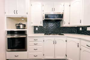 Kitchen featuring white cabinetry, appliances with stainless steel finishes, and tasteful backsplash