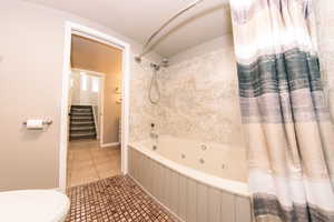 Bathroom with shower / bath combo, tile patterned floors, and toilet