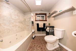 Bathroom with tile patterned flooring, shower / bath combination with curtain, and toilet