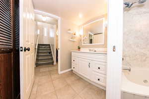 Bathroom featuring tile patterned flooring, vanity, and a jetted bathtub