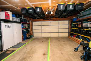 Garage with a garage door opener and white refrigerator