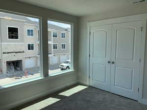 Unfurnished room with dark colored carpet and a brick fireplace