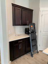 Kitchen featuring light wood finished floors and dark brown cabinetry, near kitchen pantry door