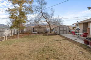 View of yard featuring a storage unit, a deck, and a patio