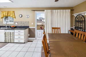 Dining area featuring sink, light tile patterned floors, a textured ceiling, and ceiling fan