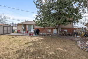 Rear view of house with a yard, a shed, and a patio area