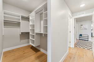 Walk in closet with light wood-type flooring