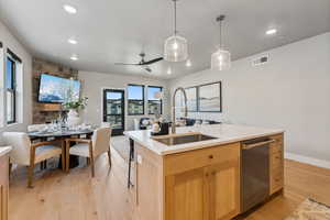 Kitchen featuring sink, light brown cabinets, dishwasher, an island with sink, and light hardwood / wood-style floors