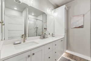 Bathroom with vanity, hardwood / wood-style flooring, and a shower with door