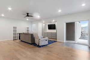 Living room with a healthy amount of sunlight, ceiling fan, and light hardwood / wood-style flooring