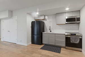 Kitchen featuring backsplash, stainless steel appliances, sink, and gray cabinetry