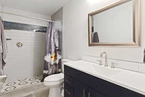 Bathroom with vanity, a shower with shower curtain, and toilet