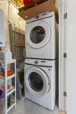 Clothes washing area with light tile patterned floors and stacked washer / dryer