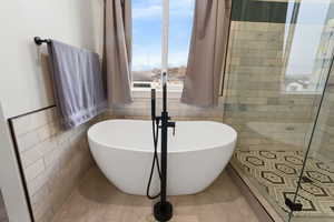 Bathroom with a bath, tile walls, and tile patterned floors