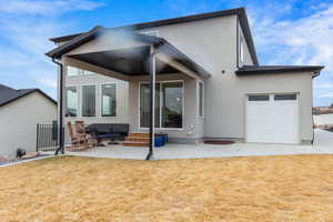 Rear view of property with a yard, a patio, and a garage