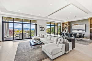 Tiled living room with a mountain view, a tray ceiling, and a healthy amount of sunlight