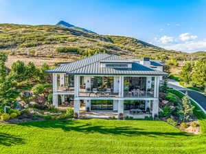 Rear view of house featuring a mountain view, a yard, and a patio area