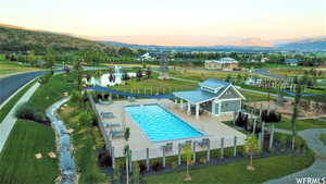 Pool at dusk featuring a water view, a water slide, and a patio