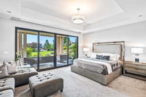 Bedroom featuring access to exterior, a tray ceiling, and carpet