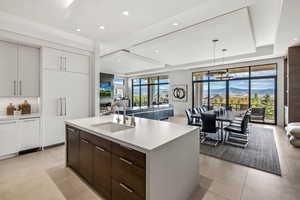 Kitchen with pendant lighting, white cabinetry, sink, a kitchen island with sink, and dark brown cabinets