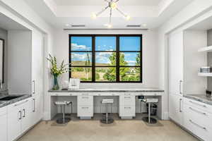 Interior space with tile patterned flooring, sink, and a raised ceiling