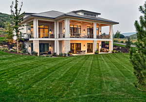 Back of property featuring a yard, a patio area, and a balcony